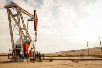an oil derrick on a barren dusty ground.