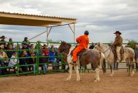 Two men ride horses in front of a large crowd