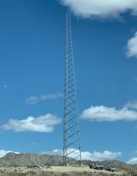 A tall communications tower rises over a desert landscape.