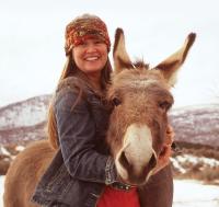 Smiling woman hugging burro around neck