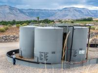A technician stands beside a BLM Colorado oil and gas well pad.