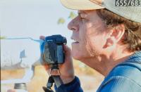 A man wearing a baseball cap holds a camera