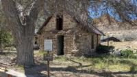 A stone cabin with a signpost in front identifying it as a cultural resource.