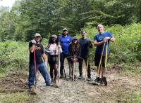People standing with shovels and tools on a dirt path