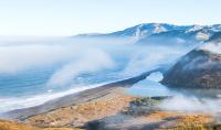 Fog descends on a mountainous beach.