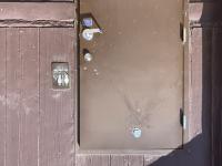 shooting of a vault toilet showing bullet holes in door.