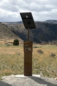 A photo of a credit card enabled kiosk in a recreation area with mountains and trees in the background