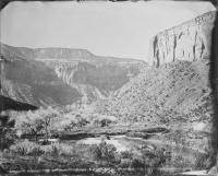 A cliff on the right descends into a valley with a river moving through it