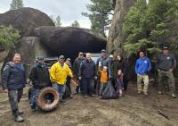 A group of people pose for a photo surrounded by trees and large boulders