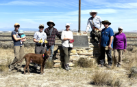 group of blm staff and volunteers stand for photo in front of marker with blue sky
