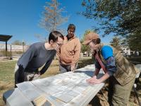 Three people looking at a map on a table in Carlsbad, New Mexico