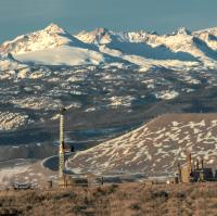 Oil and Gas rig in Wy with snow covered mountains and blue sky