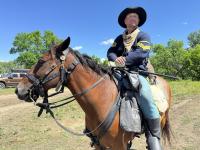 An individual posed on a horse wearing historical garb