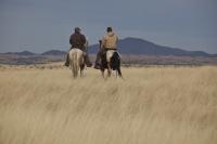 Two people ride horses in the Las Cienegas National Conservation Area.