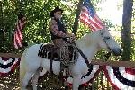 A horse with a rider and an American flag behind him. 