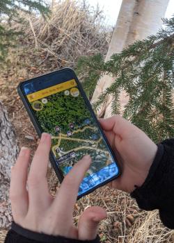 A hand holding a cell phone with the Agents of Discovery app open on it