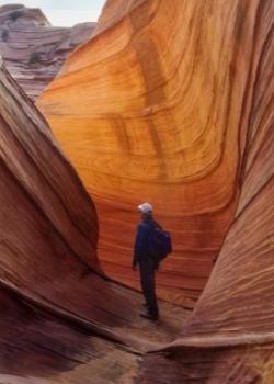 Hiker in orange and pink sandstone slot canyon