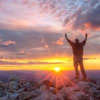 Man at sunset on top of Taylor Peak with arms raised