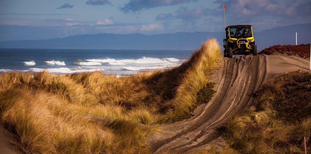 A UTV climbs a dune on the coast. Photo by Jesse Pluim, BLM.