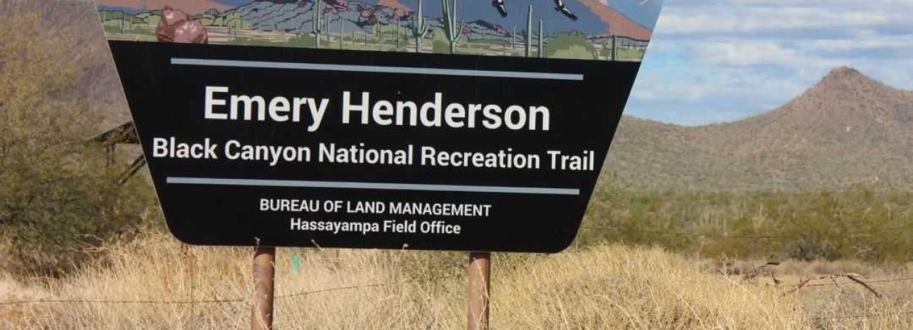 a trapezoid-shaped sign reads Emery Henderson Trailhead, Black Canyon National Recreation Trail, Bureau of Land Management, Hassayampa Field Office