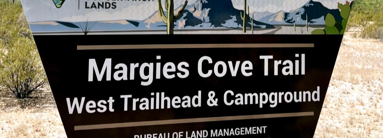 a trapezoid shaped sign with the text Margies Cove Trail West Trailhead and Campground
