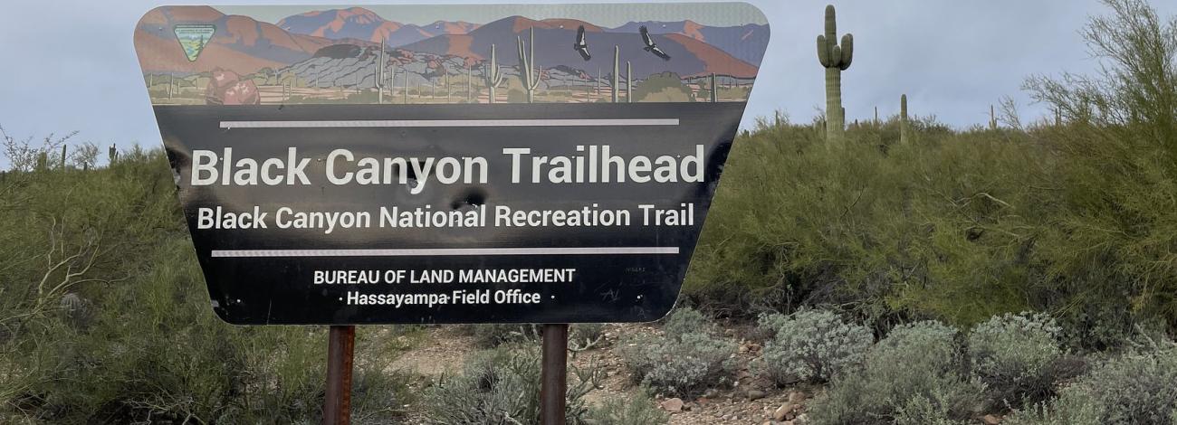 a trapezoid-shaped sign reads Black Canyon Trailhead, Black Canyon National Recreation Trail, U.S. Department of the Interior, Bureau of Land Management