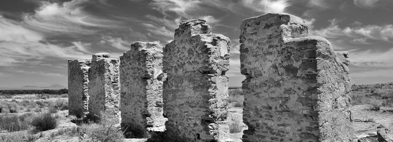 Five standing walls of Fort Craig photographed from a low angle in black and white.