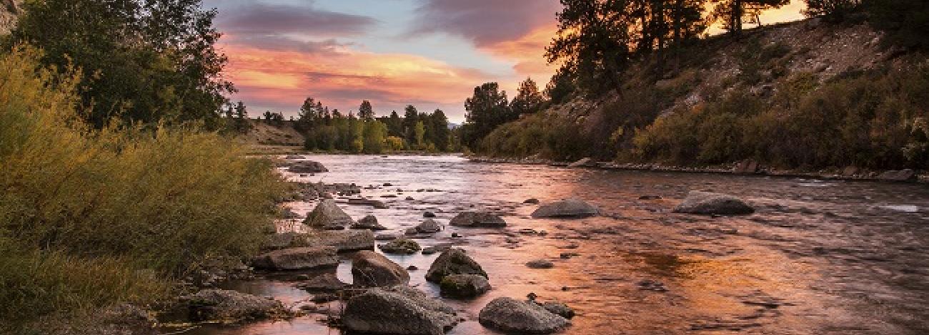 Pink and cloudy sky over a shallow riverbed during sunset