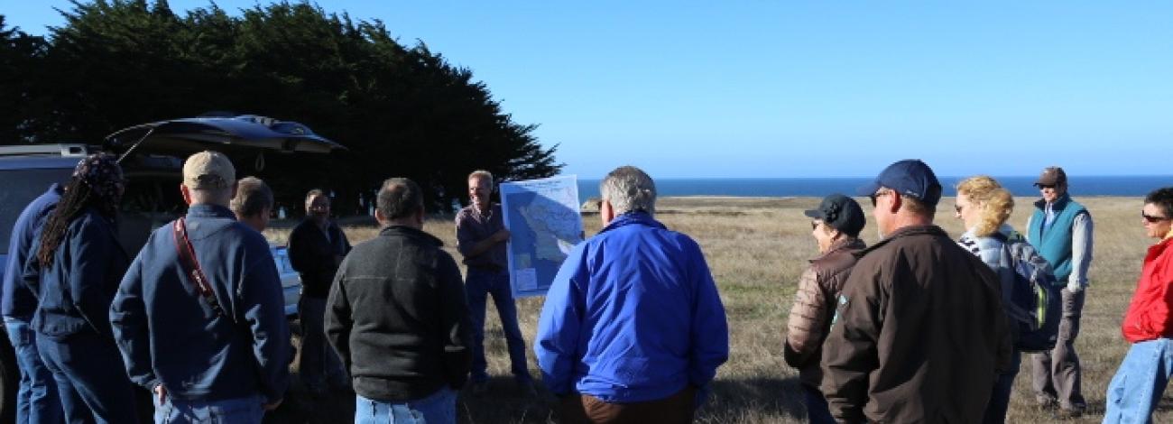 A group of people view a map while on a field tour.