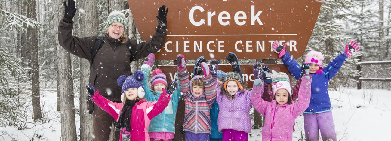 Instructor and children in front of the snowy Science Center sign