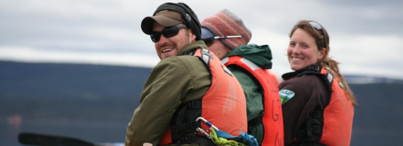 Three people wearing life vests in a raft