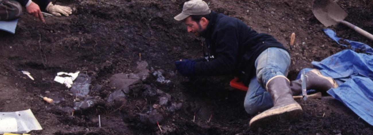 A man laying in the dirt with hand tools