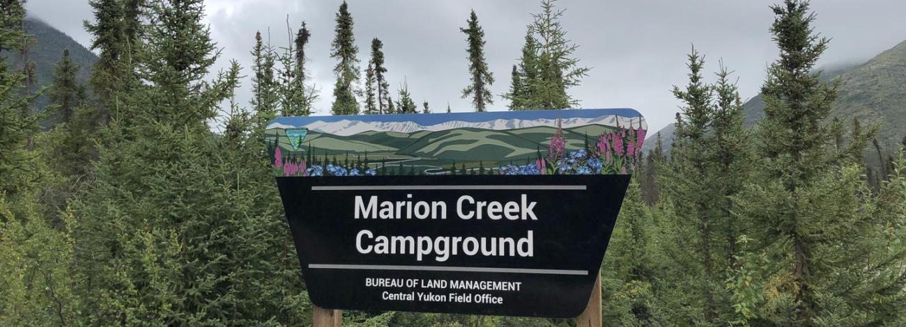 Marion Creek Campground Portal Sign with trees and mountains in the background