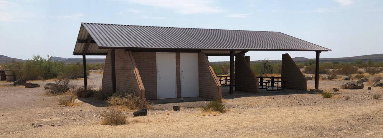 A long covered pavilion provides a shaded picnic area in the desert