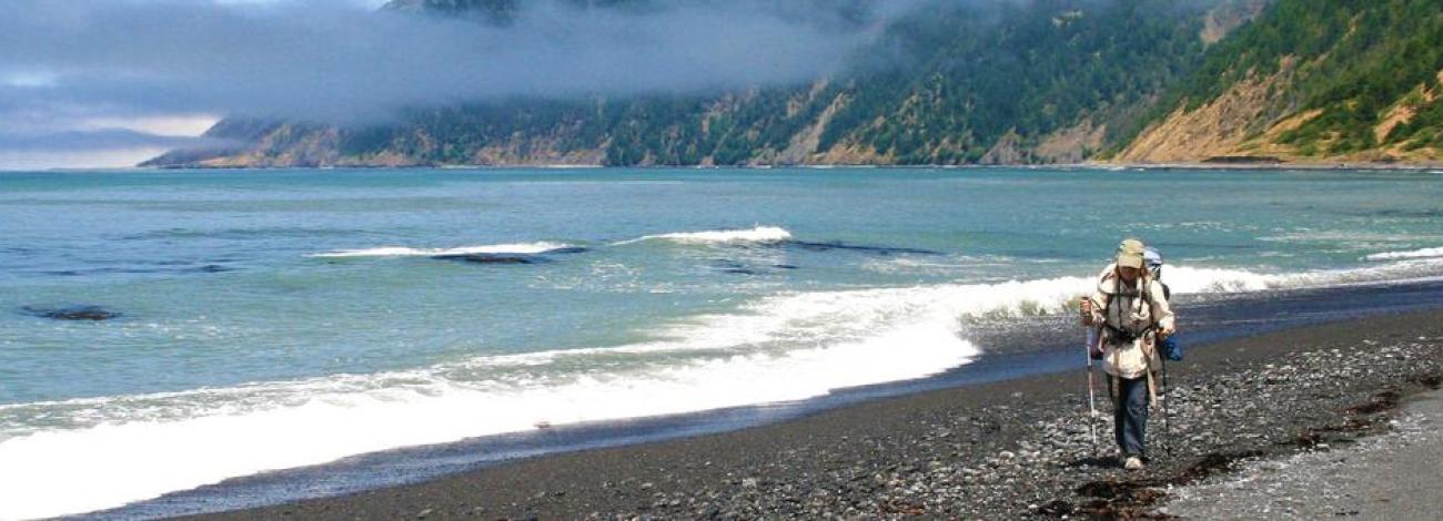 A backpacker walks along the beach in the King Range National Conservation Area.