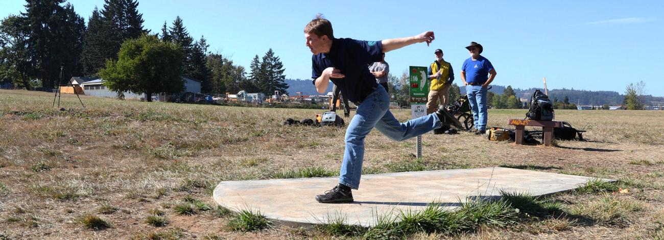 A disc golfer tees off