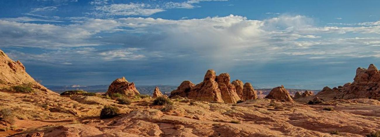 Coyote Buttes North sandstone features.  Vast landscape of sandstone with sandstone teepees in the distance and a beautiful blue sky with a touch of clouds.