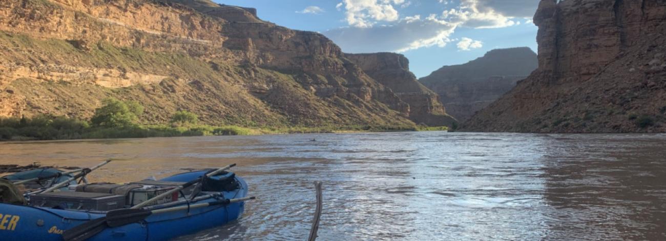 River with cliffs in background and raft on shore in foreground