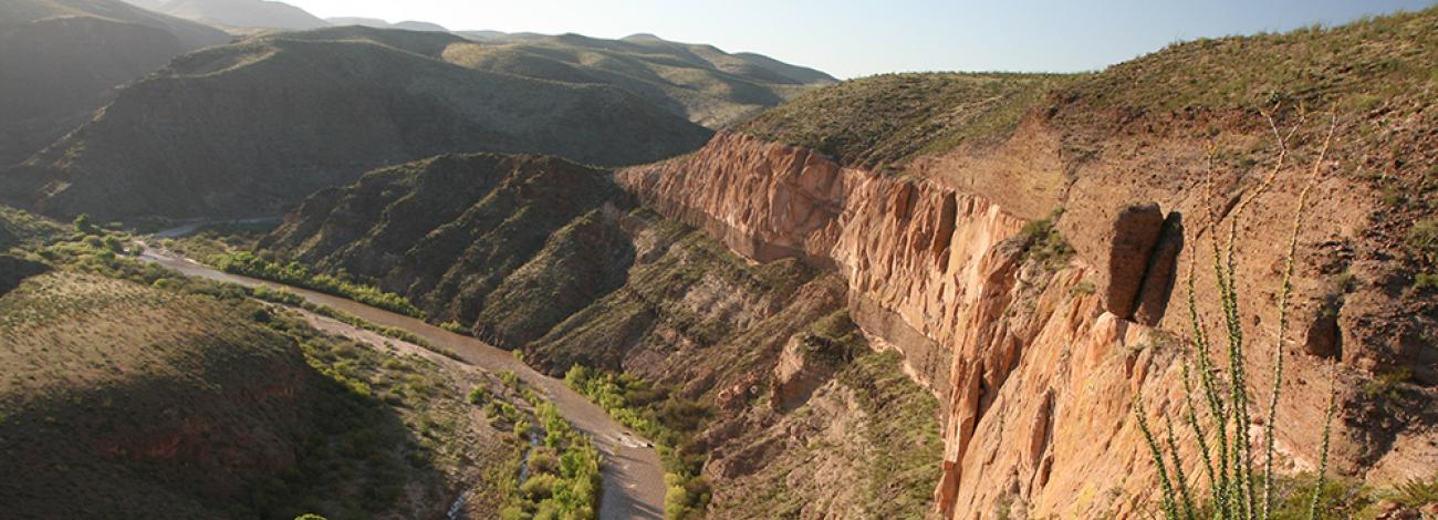 a river runs at the bottom of a canyon with steep walls