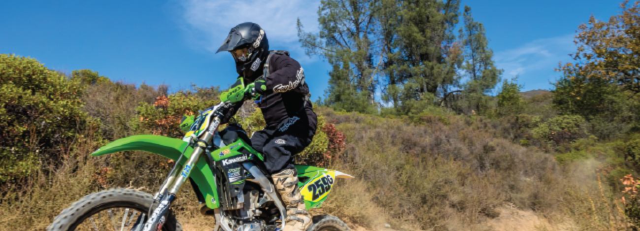 OHV on a dirt trail between evergreens. (Eric Coulter, BLM)