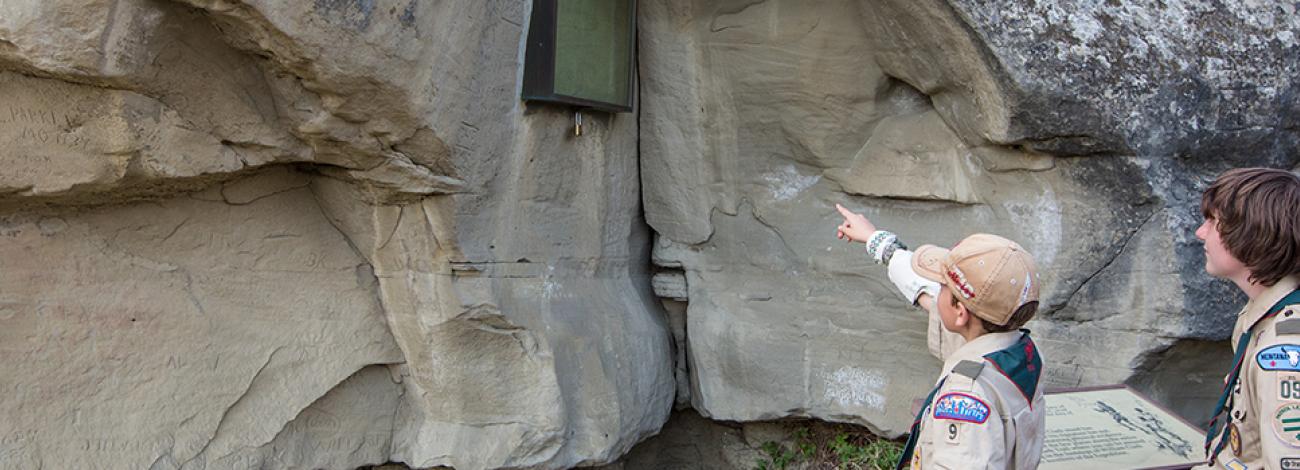 Boy scouts point at Captain William Clark's signature on Pompeys Pillar.