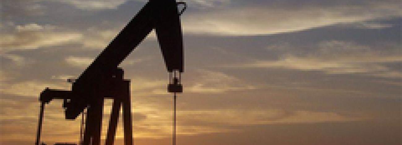 A oil and gas pump jack located in Wyoming with sunset background