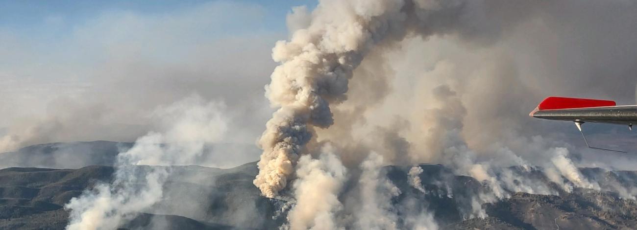 smoke from a wildfire billows up from a mountain