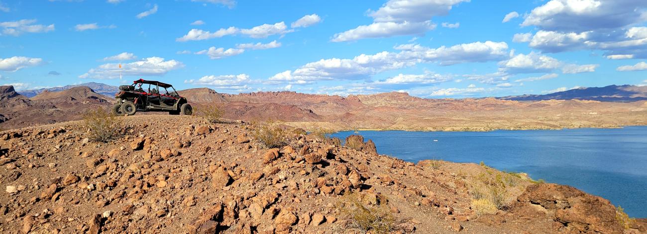 ohv overlooking lake on top of a rocky ledge on sunny and cloudy day. 