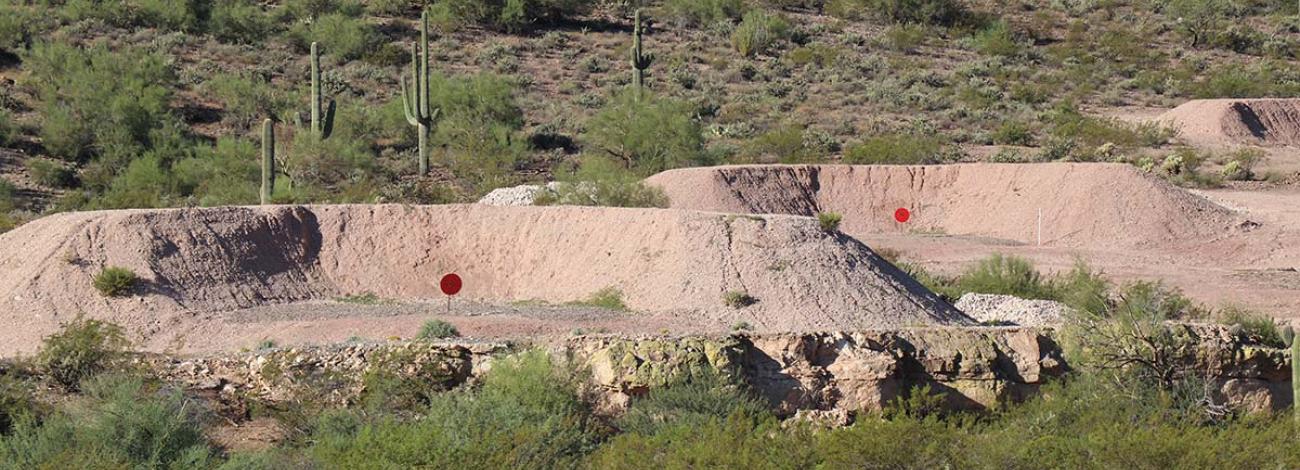 In a desert landscape, two earthen berms with red circular targets