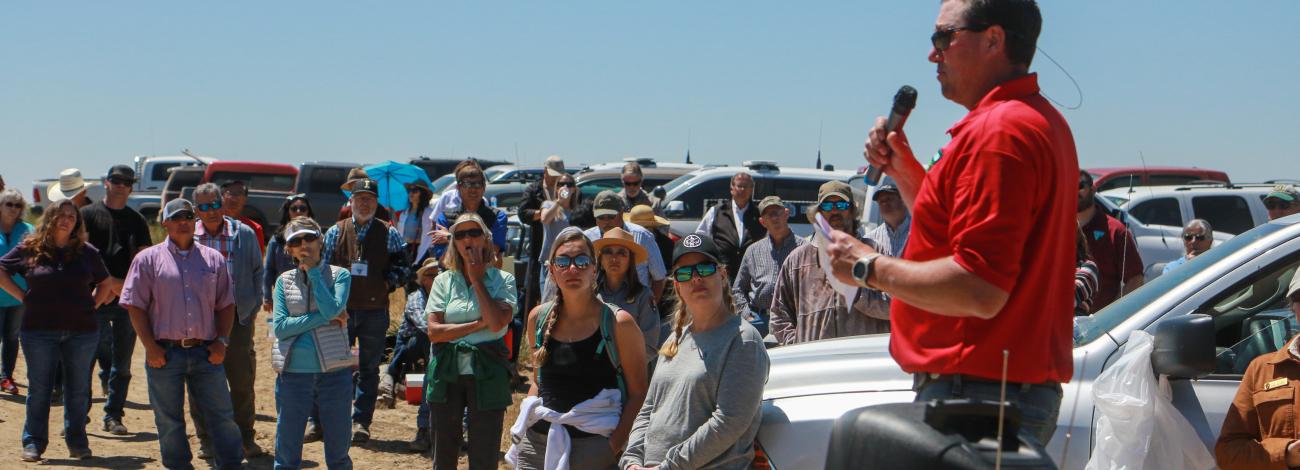 One person speaking to a group in the outdoors