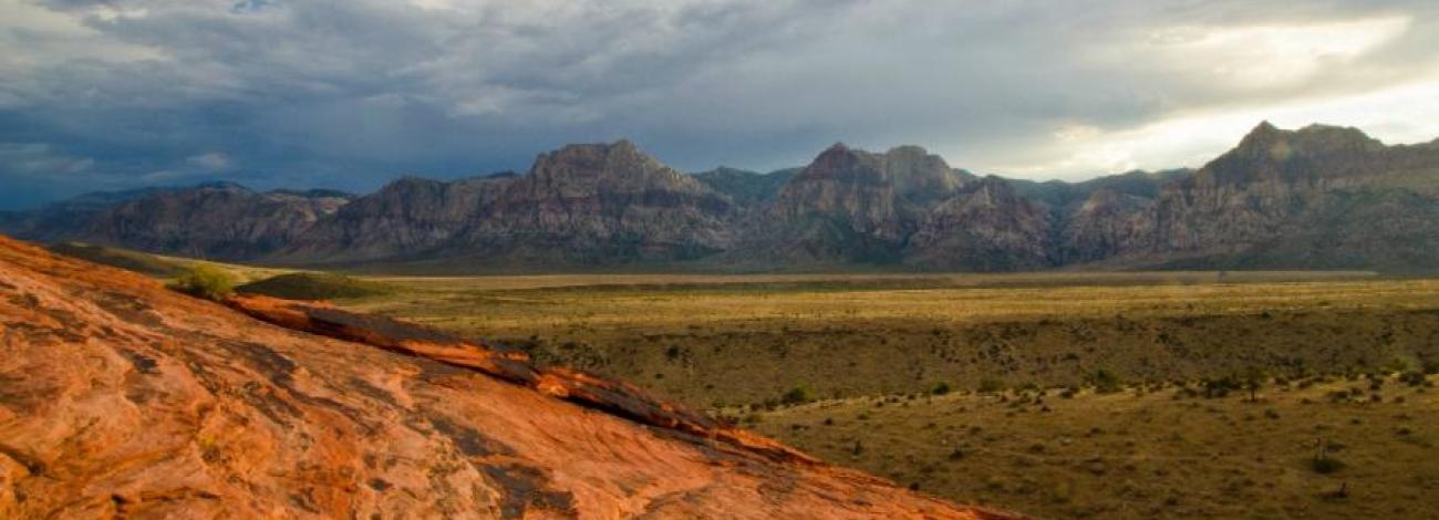 Image looking up from a hill top through the flats and multiple mountains ahead