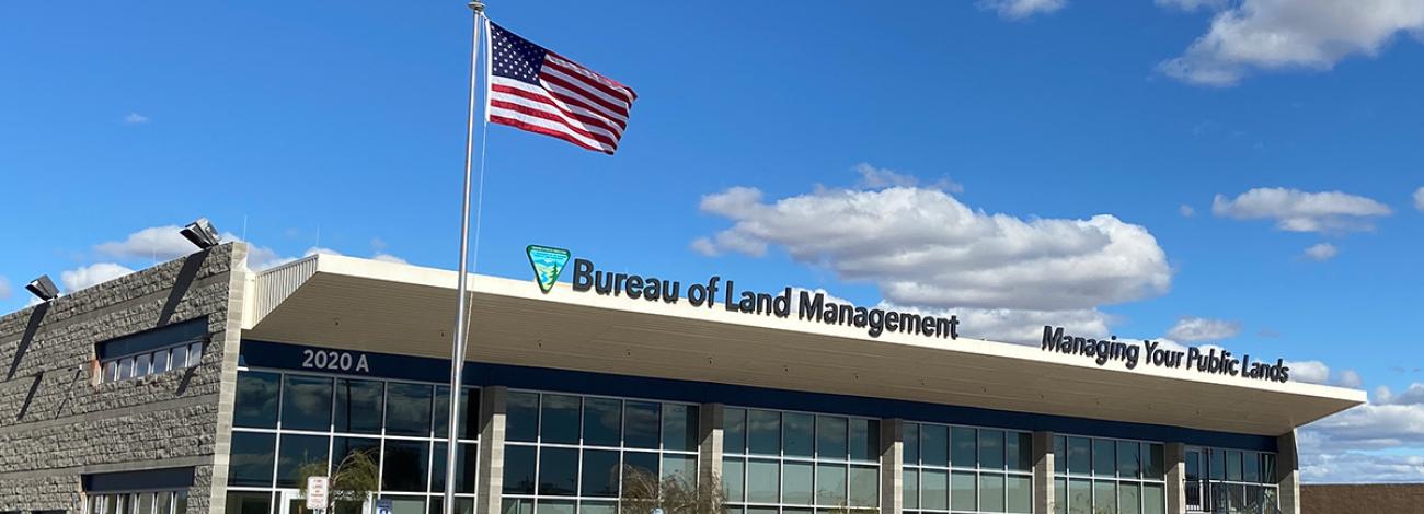 an office building with an American flag flying outside. The building sign reads Bureau of Land Management, Managing your public lands