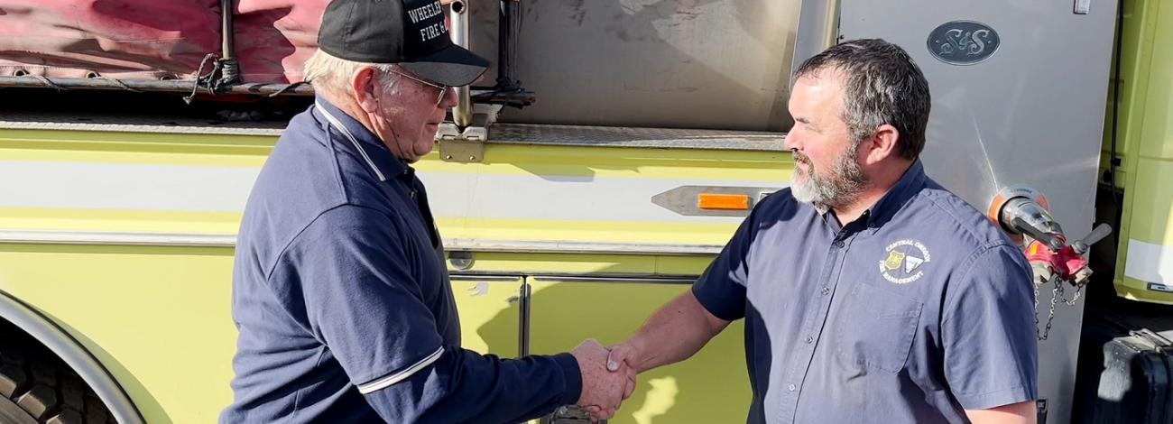 firefighters shaking hands in front of engine