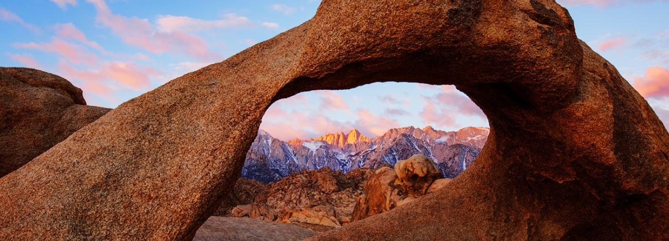 A granite arch with tall mountains in the background.